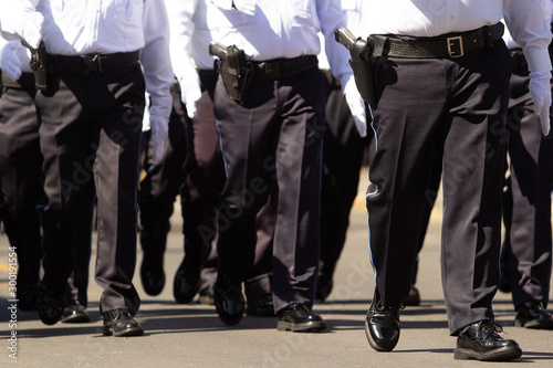 Fotografering close up of  police males, wearing dark blue pants and white shirt at a parade
