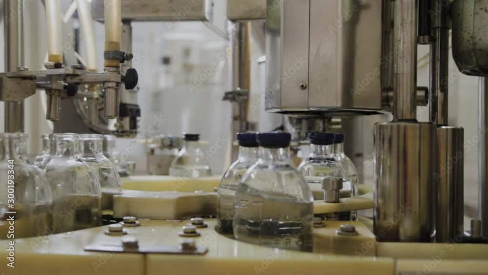 Pouring medicine on an assembly line into glass bottles for injection. Pouring medicine on an assembly line into glass bottles for injection.