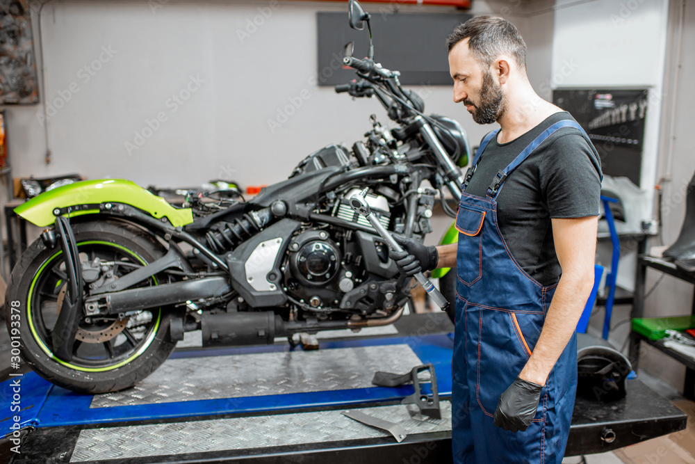 Mechanic repairing motorcycle at the workshop Mechanic repairing motorcycle at the workshop