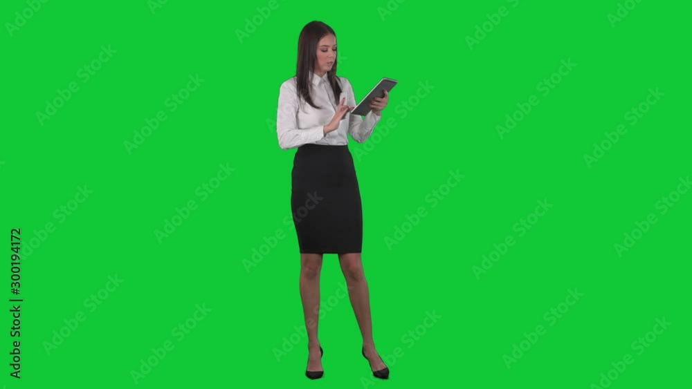 Working multitasking young business woman using tablet and having mobile phone call. Full length on green screen background. Working multitasking young business woman using tablet and having mobile phone call. Full length on green screen background.