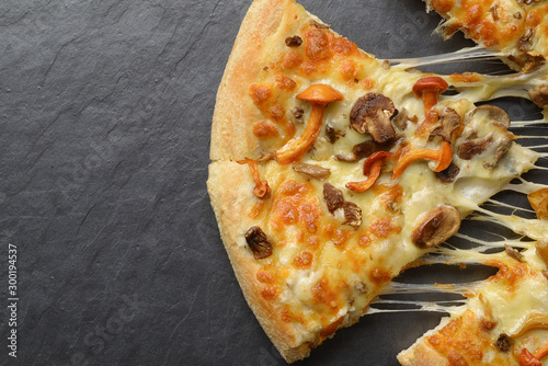 Mushroom pizza with melting cheese on the `black slate background photo