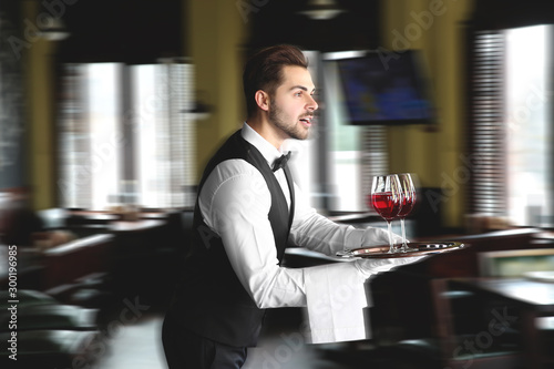 Young hurrying waiter with ...
