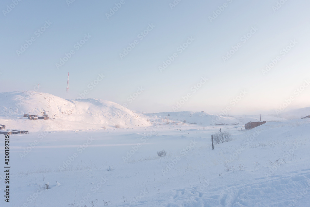 a valley covered with deep white snow and hills with high television radio towers on a hill on a frosty winter day in the far north a valley covered with deep white snow and hills with high television radio towers on a hill on a frosty winter day in the far north