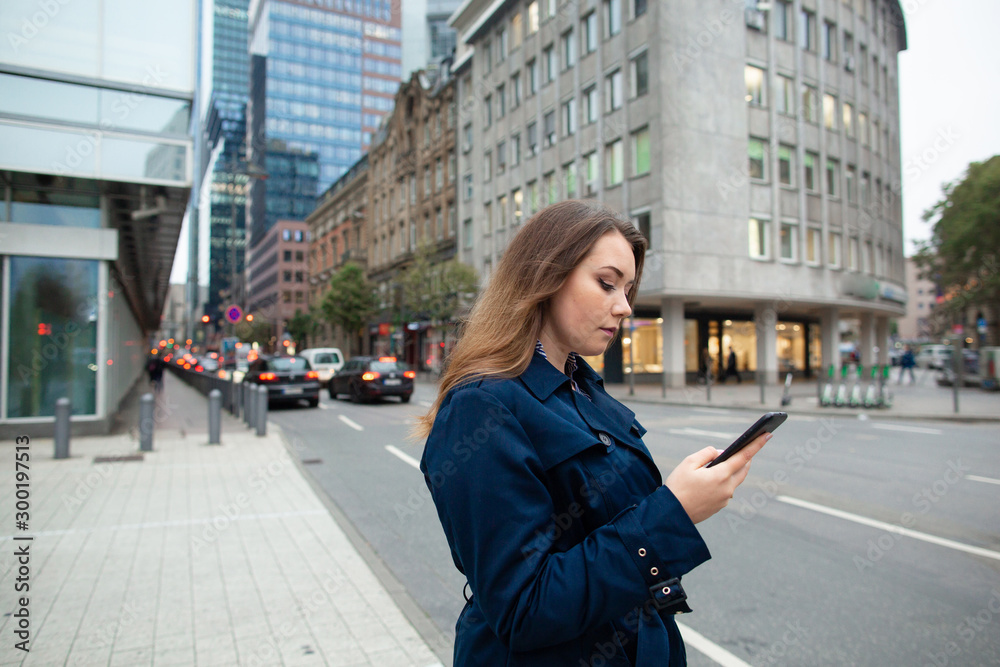 Fototapeta premium Business woman looking a location in the phone, for a business meeting. Half length photo. Germany, Frankfurt