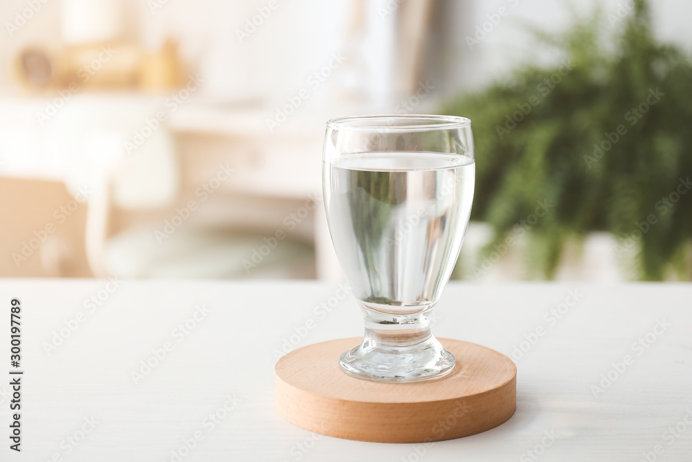 Glass of fresh water on table in room Glass of fresh water on table in room