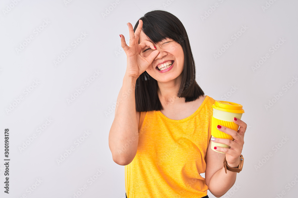 Young beautiful Chinese woman drinking take away coffee over isolated white background with happy face smiling doing ok sign with hand on eye looking through fingers