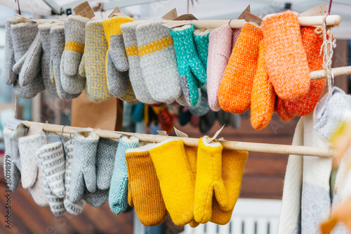 Colorful knitted traditional European warm clothes for cold winter days - close-up view. Mittens at winter Christmas market are lovely souvenir for tourists from Europe.