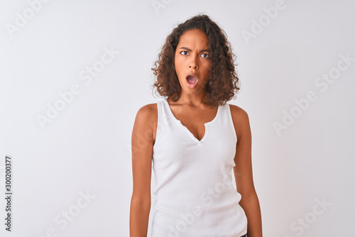 Young brazilian woman wearing casual t-shirt standing over isolated white background In shock face, looking skeptical and sarcastic, surprised with open mouth