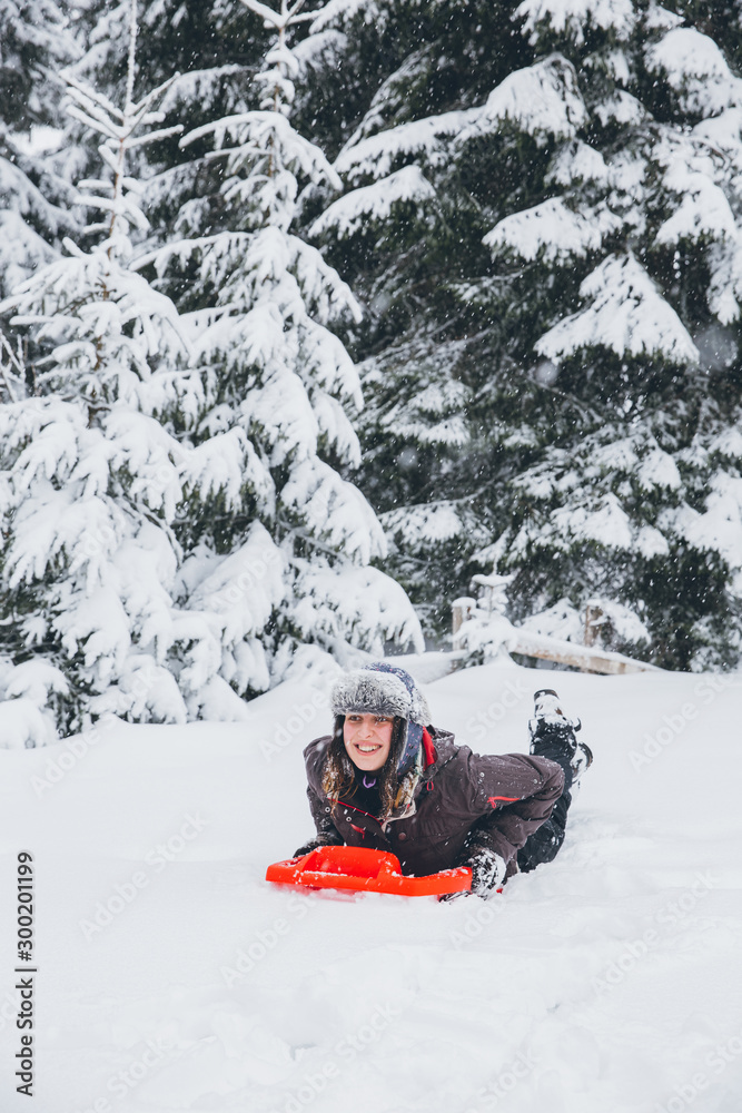 Woman having fun in heavy snow with a sleigh.