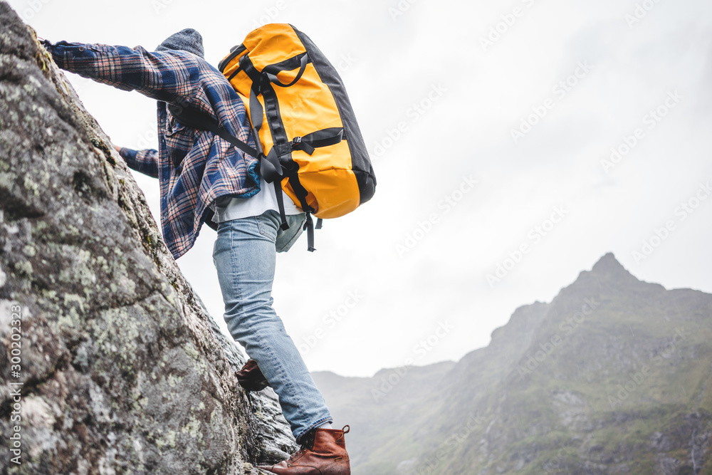 Brave lifestyle climber with professional backpack climb to the rock. Active fearless tourist swarm up on mountain - obrazy, fototapety, plakaty 