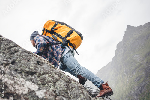 Young extreme lifestyle climber with professional backpack climb to the rock. Active fearless professional tourist swarm up on mountains
