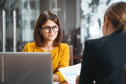 Group of happy business people have meeting at workplace in office. Two positive woman working together using modern laptop for working concept