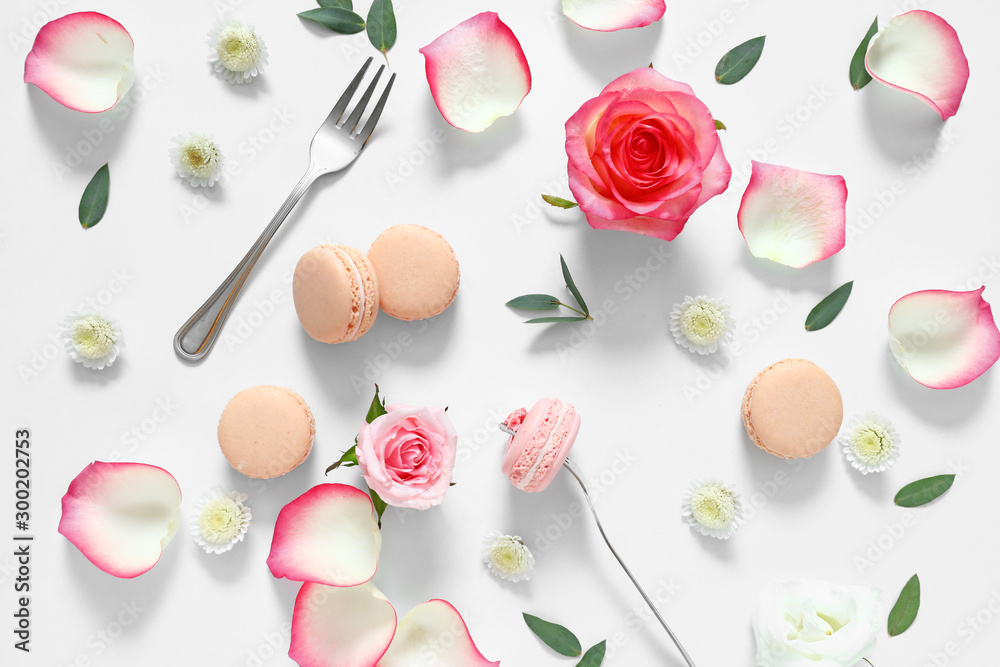 Tasty macarons with rose flowers on white background