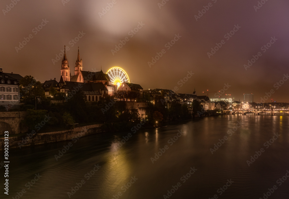 Dramatic night cityscape of the Basel old town skyline from the Rhine river, Switzerland.