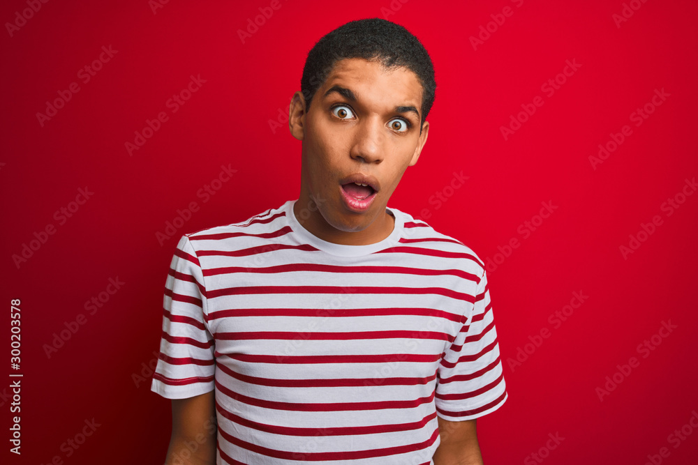 Young handsome arab man wearing striped t-shirt over isolated red background In shock face, looking skeptical and sarcastic, surprised with open mouth Young handsome arab man wearing striped t-shirt over isolated red background In shock face, looking skeptical and sarcastic, surprised with open mouth
