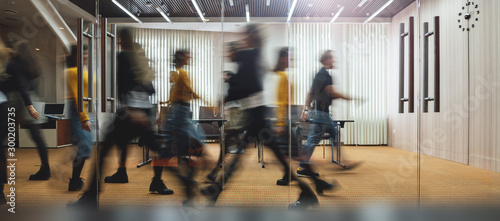Businesspeople walking at modern office. Group of business employees at coworking center. Motion blur. Concept work process. Wide image photo