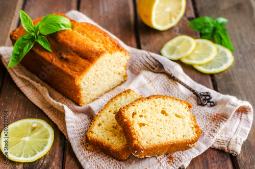 Lemon pound cake on rustic wooden background with lemon.