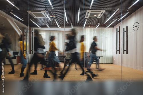 Group of business people walking at modern open space. Team of business employees at coworking center. Motion blur. Concept work in process photo