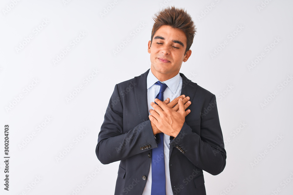 Young handsome businessman wearing suit standing over isolated white background smiling with hands on chest with closed eyes and grateful gesture on face. Health concept. Young handsome businessman wearing suit standing over isolated white background smiling with hands on chest with closed eyes and grateful gesture on face. Health concept.