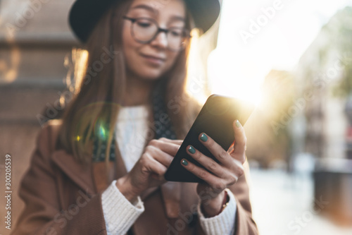 Woman holding in hands mobile phone. Girl traveler in hat using gadget cellphone in europe sunlight city. Digital internet lifestyle mockup. Close up technology smartphone online connect