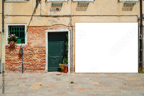 Fototapeta Naklejka Na Ścianę i Meble -  building facade of old house with pots of flowers on windowsill on street of old European city placard empty display mock-up