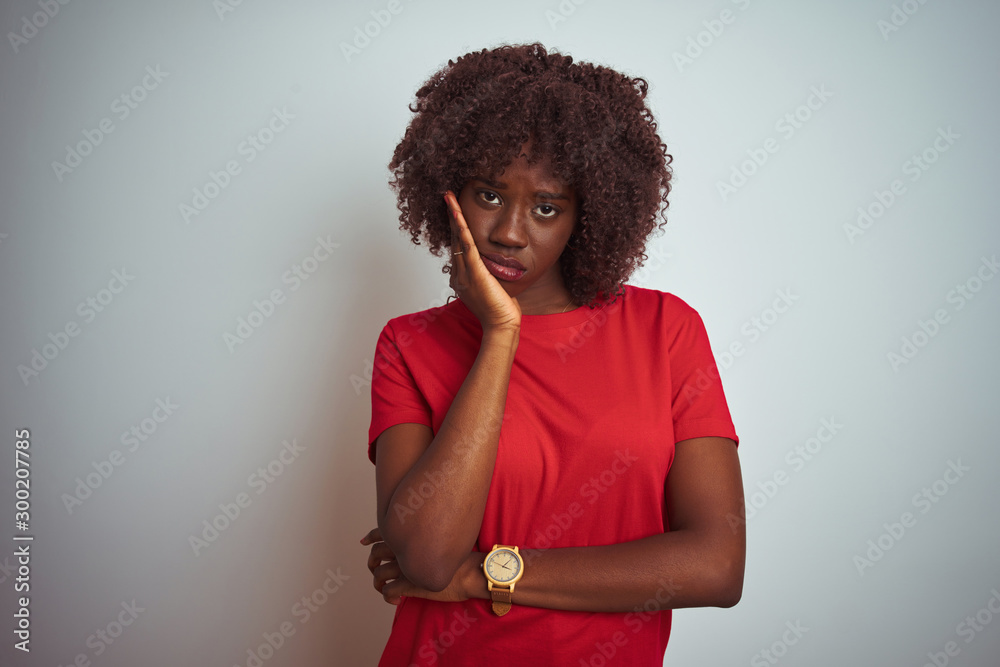 Young african afro woman wearing red t-shirt over isolated white background thinking looking tired and bored with depression problems with crossed arms. Young african afro woman wearing red t-shirt over isolated white background thinking looking tired and bored with depression problems with crossed arms.