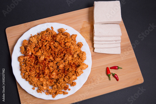 Chorizo vegano hecho con tofu firme, paprika y especias en una tabla de madera sobre fondo negro.