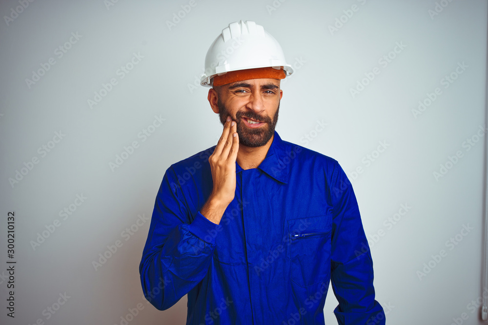 Handsome indian worker man wearing uniform and helmet over isolated white background touching mouth with hand with painful expression because of toothache or dental illness on teeth. Dentist concept.