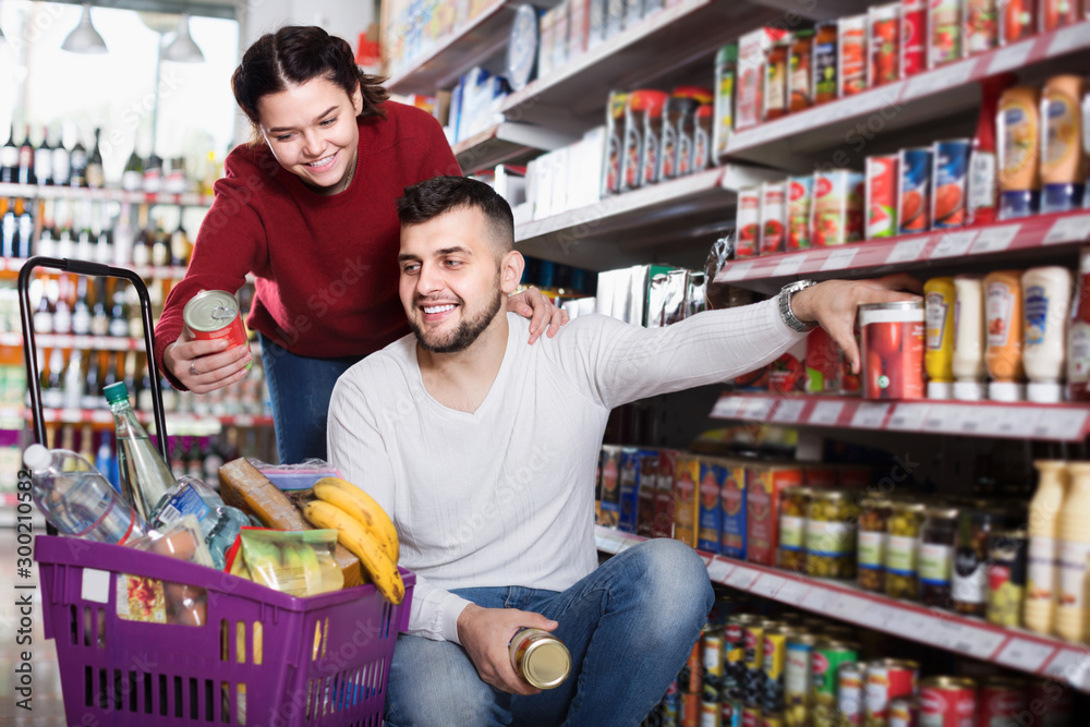 Smiling young family purchasing tinned food