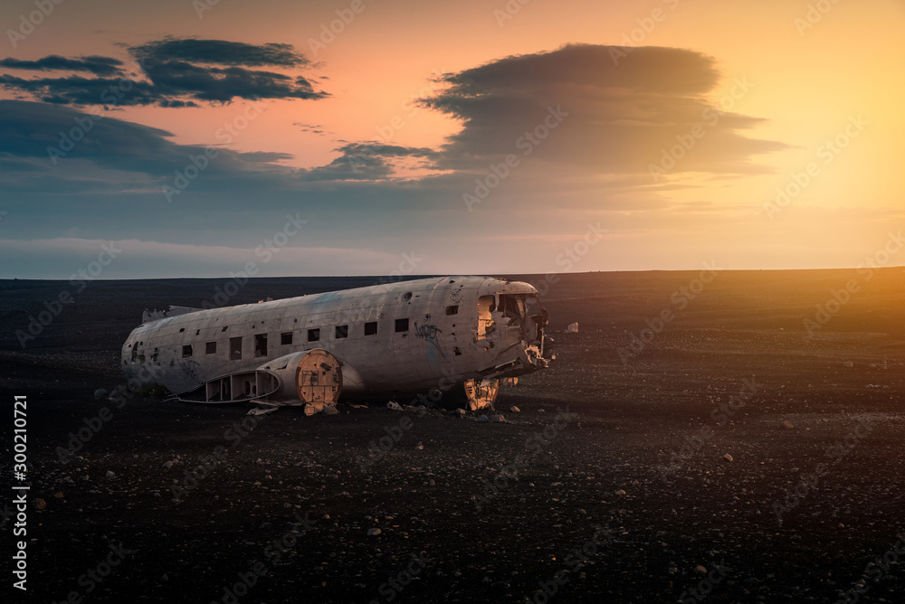 Crushed plane Dakota on black beach at the sunset