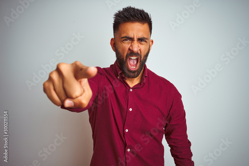 Young indian man wearing red elegant shirt standing over isolated grey background pointing displeased and frustrated to the camera, angry and furious with you