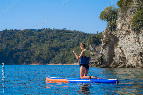 Summer holidays vacation travel. SUP Stand up paddle board. Young woman sailing on beautiful calm lagoon © Alexey Pelikh