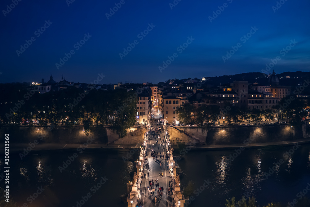 Bridge to Castle of Holy Angel with people at night in Rome historic centre, view from above.