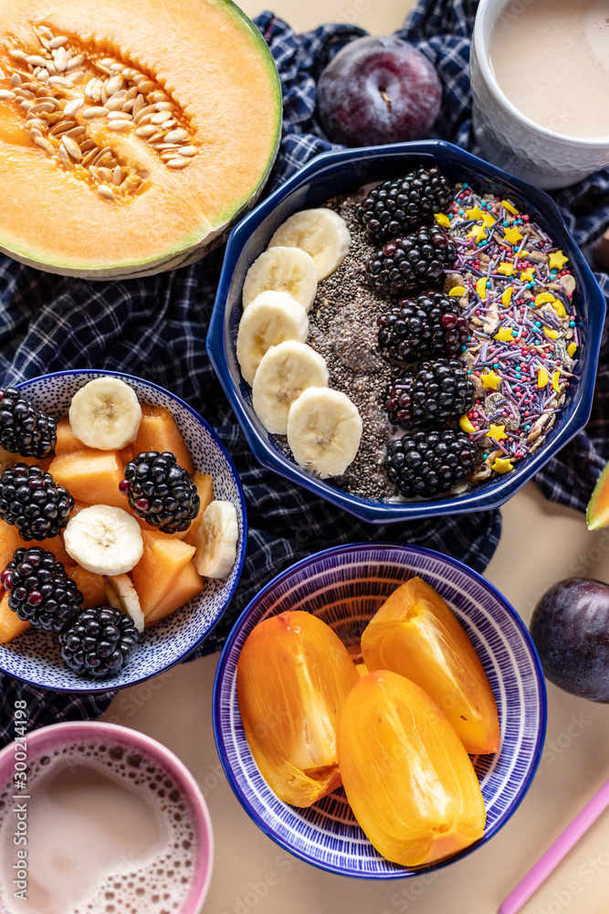 Breakfast bowl with oatmeal, yogurt, blackberries, persimmon, melon and chia seeds, top view Breakfast bowl with oatmeal, yogurt, blackberries, persimmon, melon and chia seeds, top view