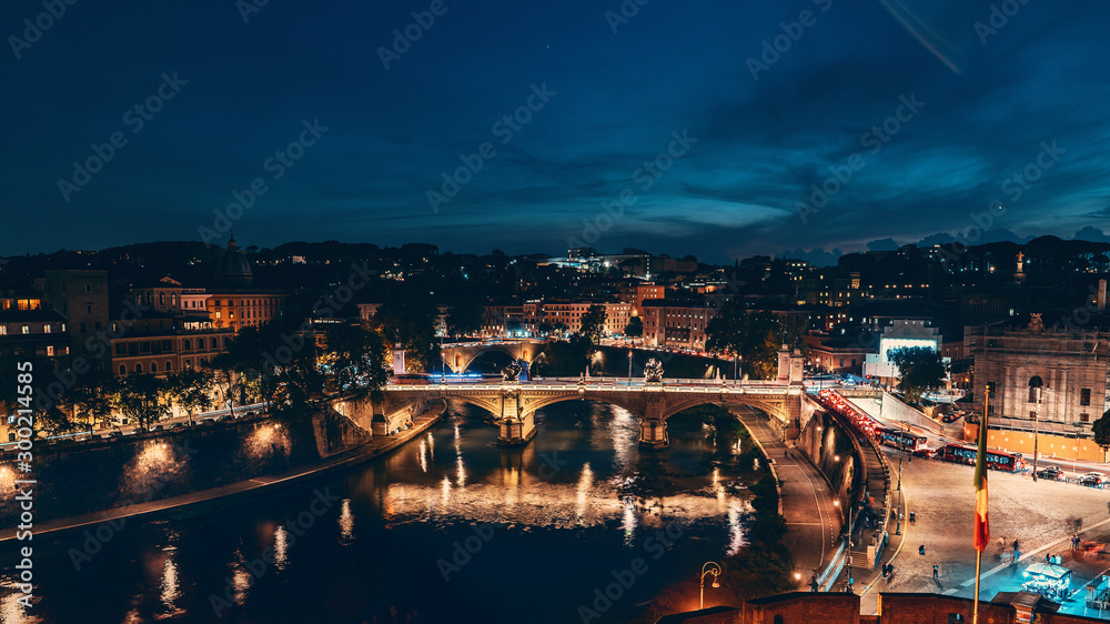 Obraz premium St Angel Bridge or Ponte Sant Angelo or Aelian Bridge on Tiber river at night with city illumination in Rome, Italy, view from above.