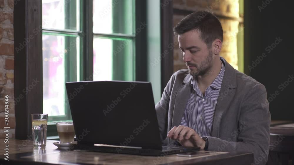 Close-up of young Caucasian man while working on laptop computer in coffee shop Close-up of young Caucasian man while working on laptop computer in coffee shop