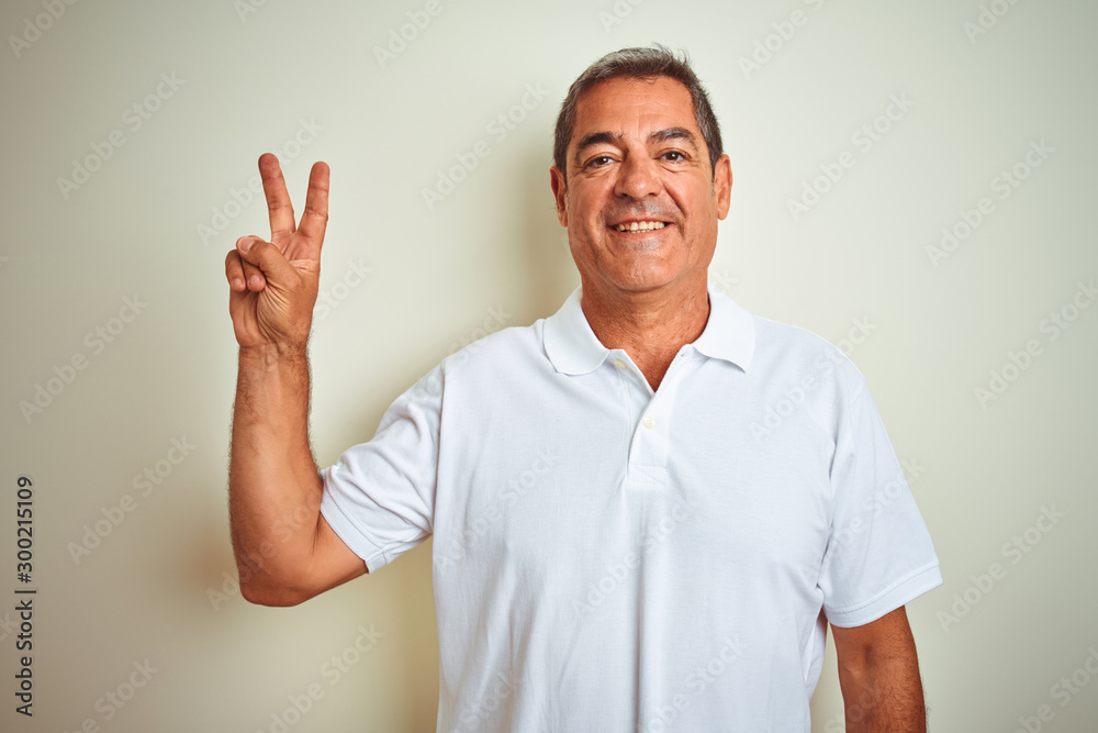 Handsome middle age man wearing polo standing over isolated white background smiling with happy face winking at the camera doing victory sign. Number two. Handsome middle age man wearing polo standing over isolated white background smiling with happy face winking at the camera doing victory sign. Number two.