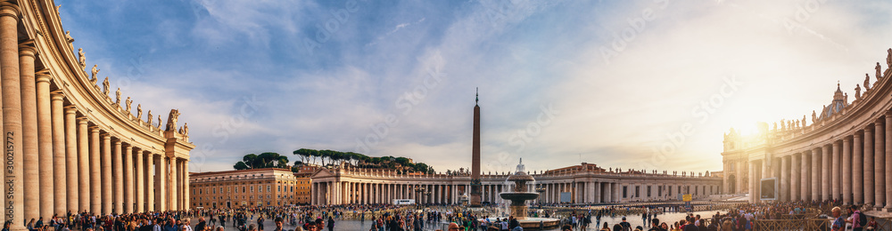 Vatican City, Rome, Italy - Circa October 2019: Panorama of Piazza San Pietro square and Basilica di San Pietro at Vatican City with tourists on street in sunset.