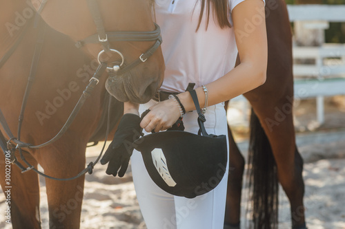Close image, the rider woman with his horse before the competition holding helmet.