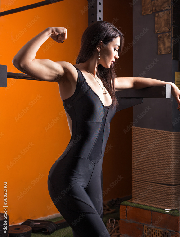 Photo of gorgeous strong young woman in gym. Fitness girl showing biceps.  Sport, healthy lifestyle, gym, good body condition, women health. Stock  Photo