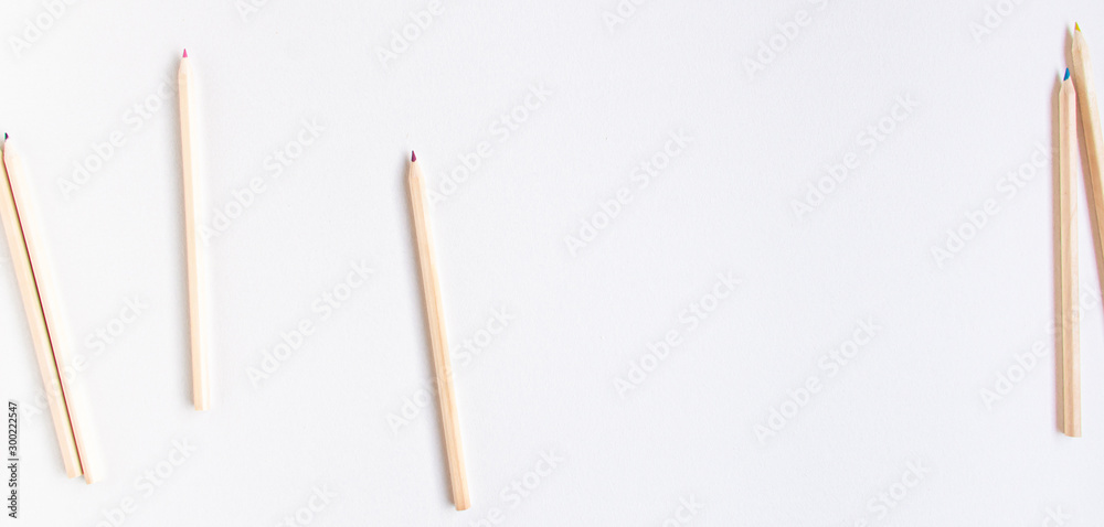 Top view flat lay of a group of wooden pencils that roll out of the frame in different directions leaving a blank background. Education concept. Banner with space for text. Top view flat lay of a group of wooden pencils that roll out of the frame in different directions leaving a blank background. Education concept. Banner with space for text.