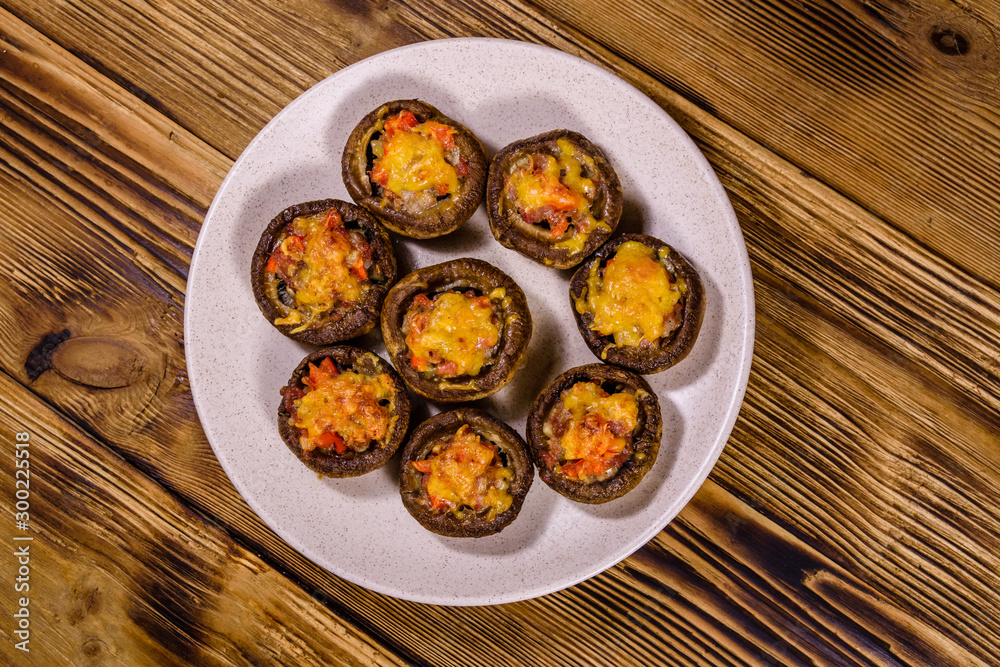 Baked champignons stuffed with minced meat and cheese in plate on a wooden table. Top view