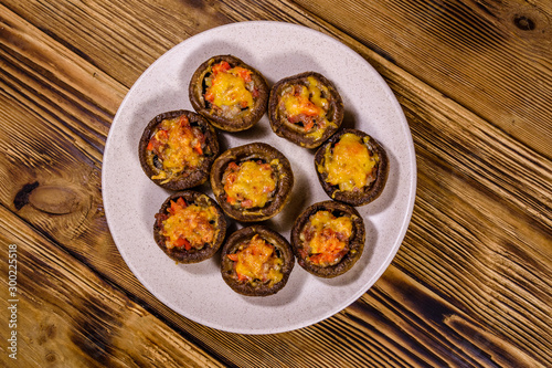 Baked champignons stuffed with minced meat and cheese in plate on a wooden table. Top view