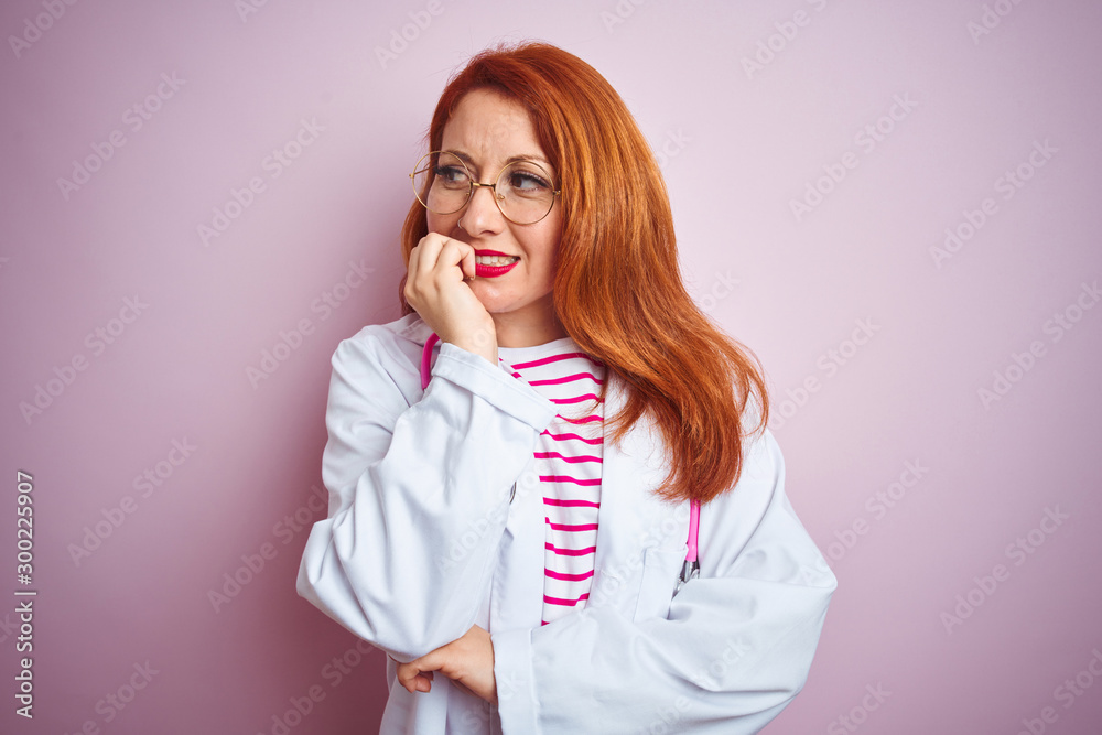 Young redhead doctor woman wearing glasses over pink isolated background looking stressed and nervous with hands on mouth biting nails. Anxiety problem. Young redhead doctor woman wearing glasses over pink isolated background looking stressed and nervous with hands on mouth biting nails. Anxiety problem.