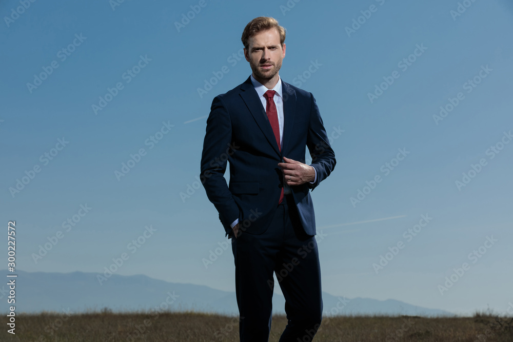 Confident businessman fixing his jacket while standing Confident businessman fixing his jacket while standing