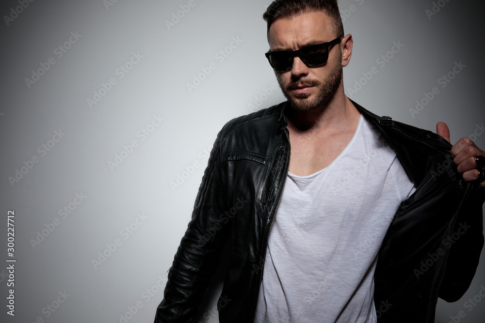 Fototapeta premium Serious looking dramatic man fixing and pulling his jacket