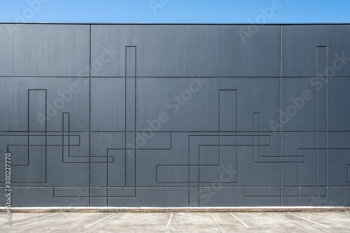 Dark gray concrete wall of industrial building with geometric pattern with empty parking spaces
