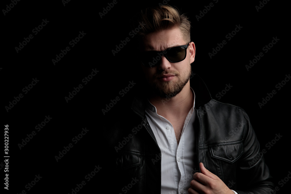 Obraz premium casual man wearing sunglasses standing and arranging jacket
