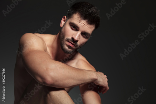 dramatic naked guy holding arm on knee