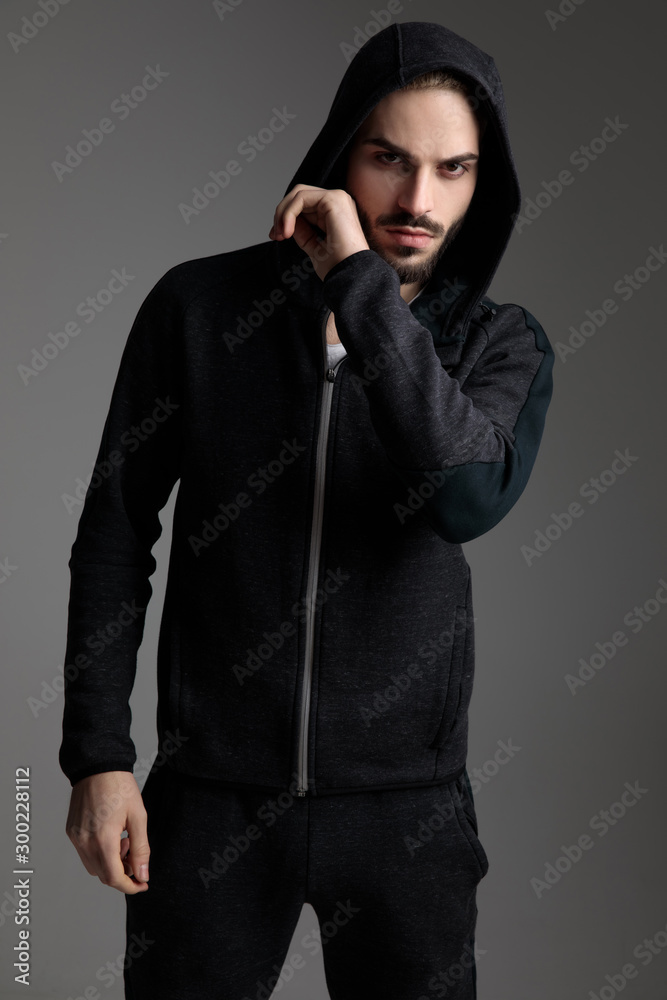 casual man standing with hood on head and touching chin casual man standing with hood on head and touching chin